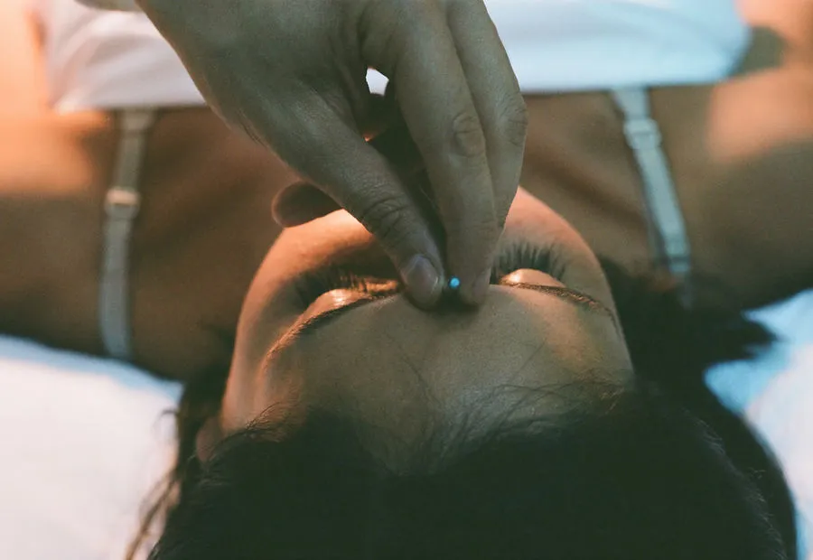 Pose d’une aiguille fine entre les sourcils, lors d’un soin d’acupuncture esthétique du visage