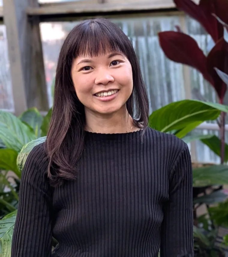 Portrait de Jessica Chan, souriante, devant un feuillage