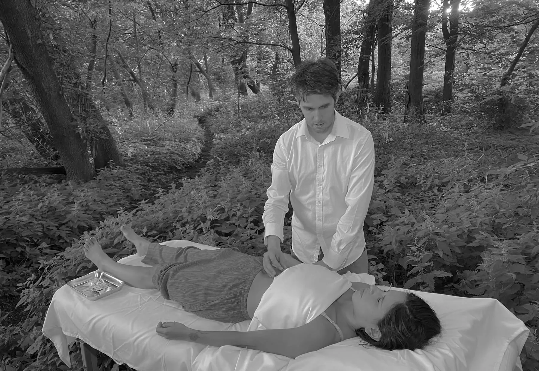 An outdoor session in black and white: the practitioner standing by the table